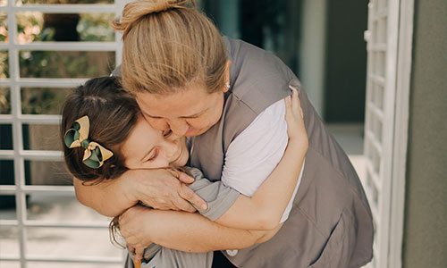 Aluna abraçada fortemente com funcionaria em escola cristã bilíngue
