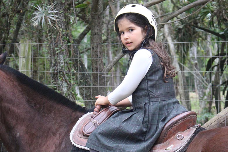 Aluna montada em um cavalo em escola cristã bilíngue